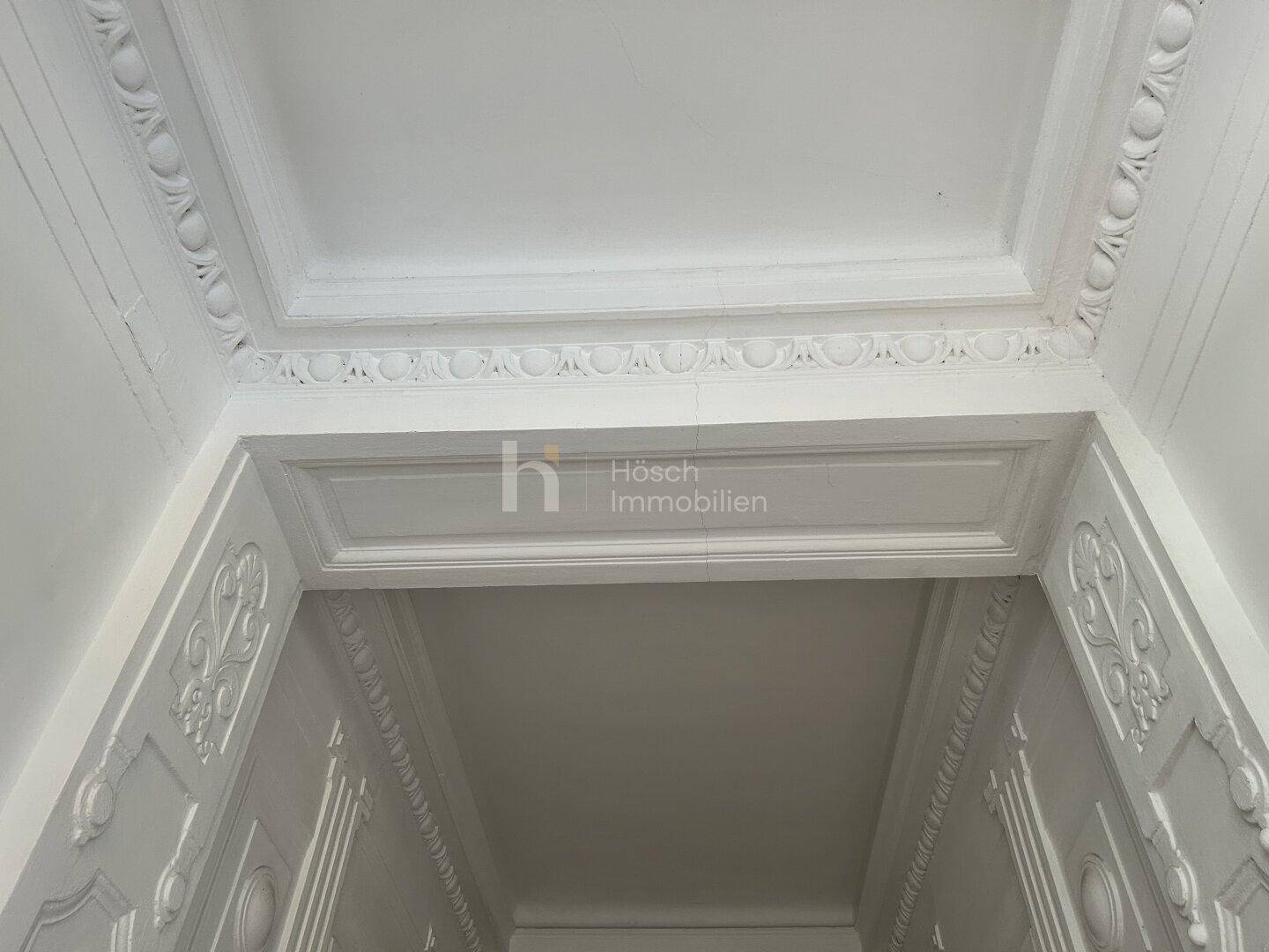 Detailaufnahme der Stuckverzierungen an der Decke und den Türrahmen im Eingangsbereich.