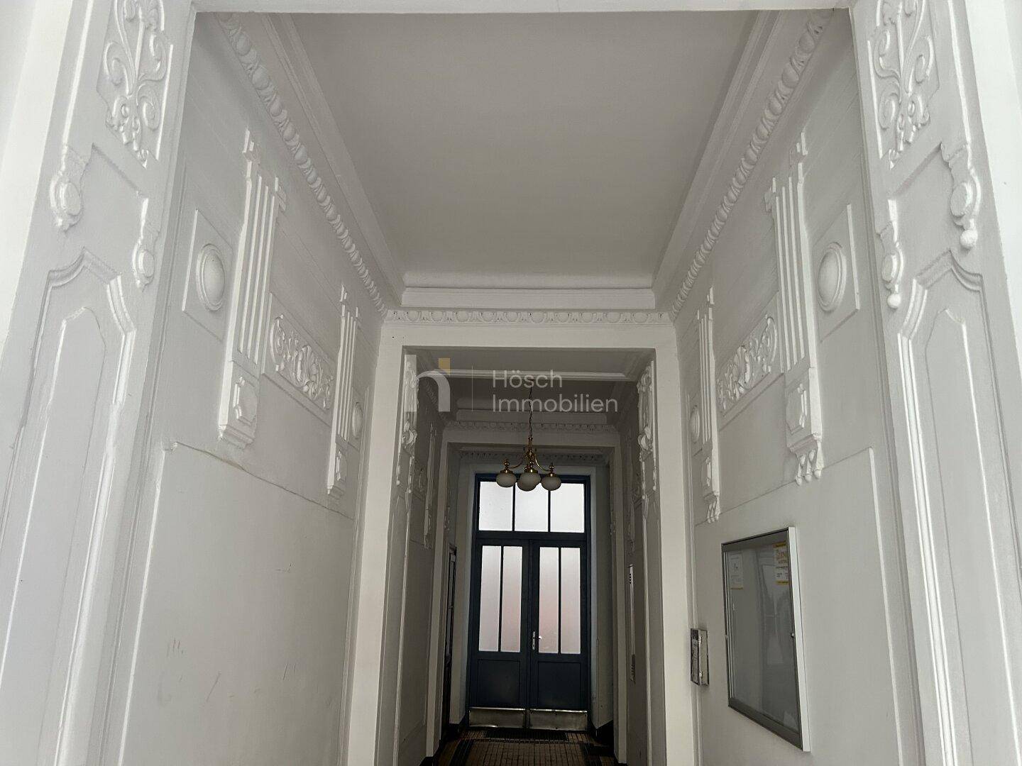 Repräsentativer Eingangsbereich mit Stuckverzierungen an Decke und Wänden, der Eleganz ausstrahlt.