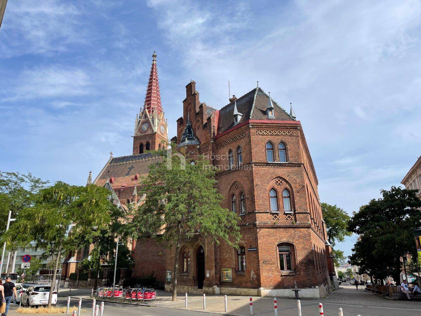 Historisches Backsteingebäude mit markantem Kirchturm in einer städtischen Umgebung.