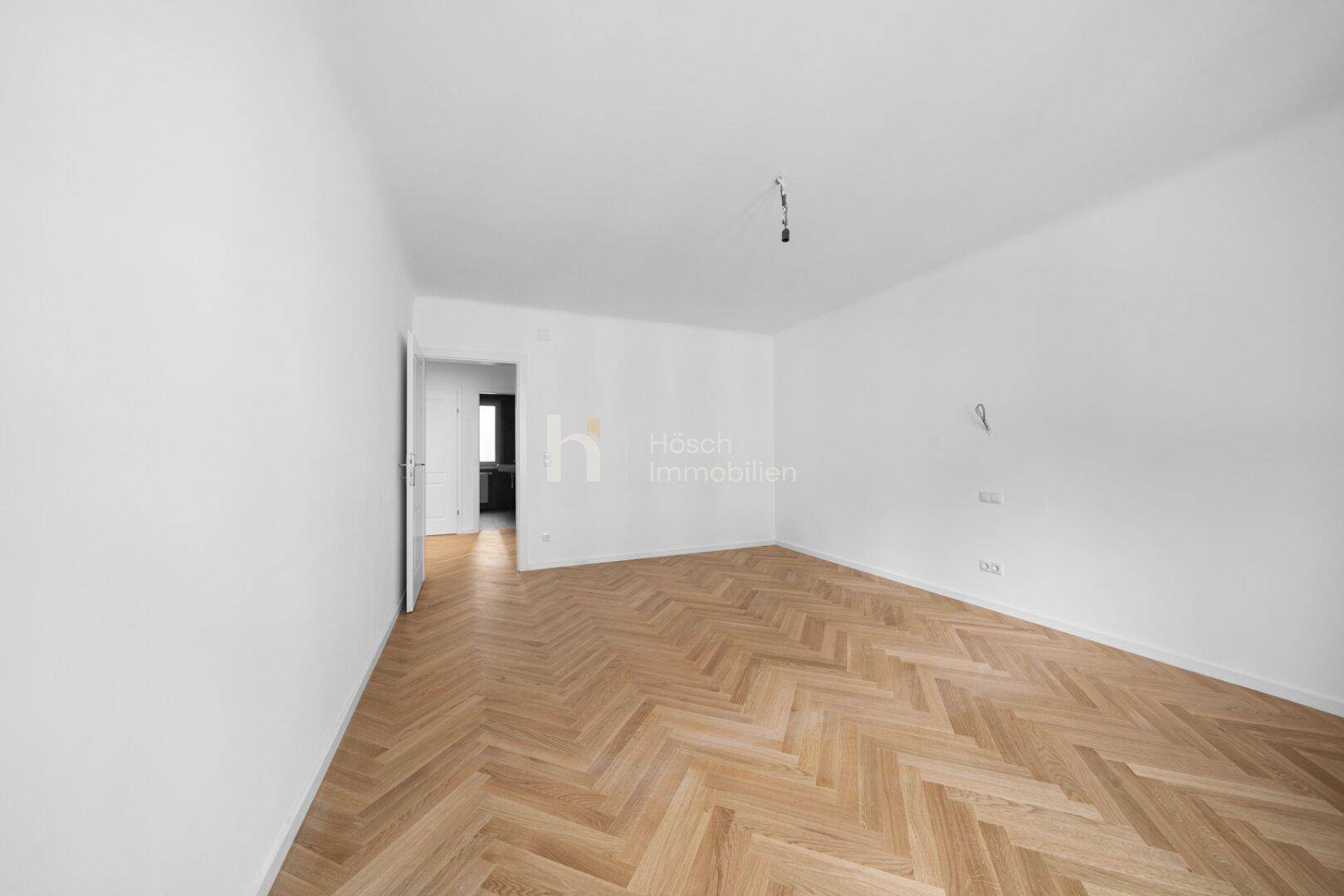 Leerer Raum mit Fischgrätparkett und weiß gestrichenen Wänden, ideal für individuelle Gestaltung.