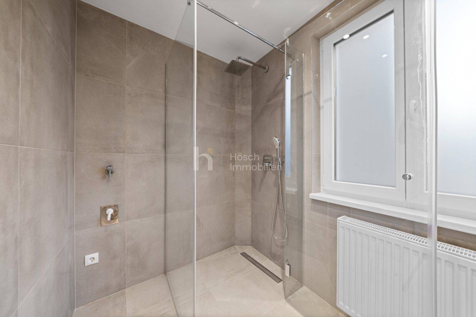 Modernes Badezimmer mit begehbarer Dusche, Regendusche und großformatigen Fliesen.