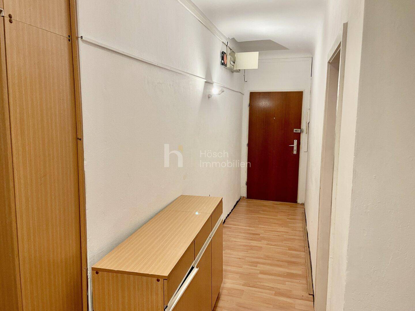 Eingangsbereich mit Holzschrank und der Wohnungstür, hell und funktional.