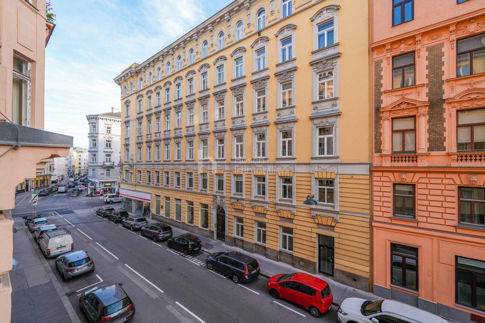 Historisches Gebäude mit gelber Fassade, vielen Fenstern und Blick auf die Straße.