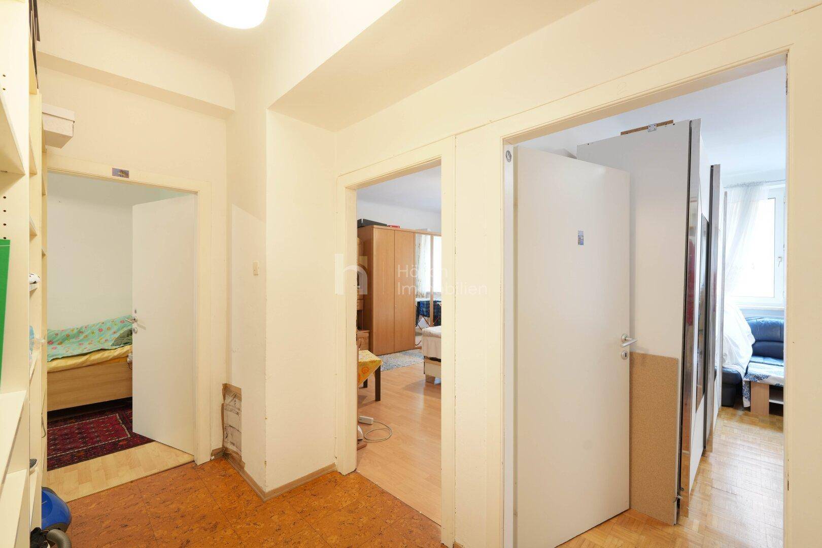 Flur mit Korkboden und Zugang zu mehreren Zimmern, darunter ein Schlafzimmer.