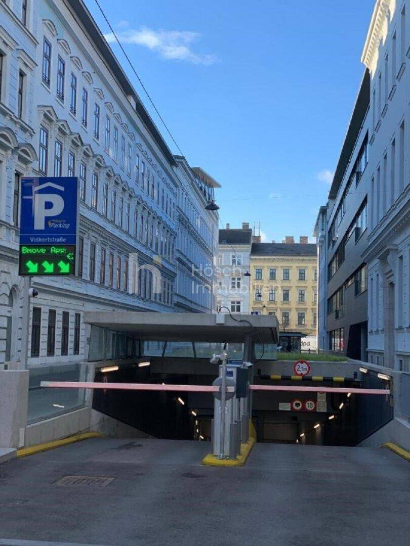 Einfahrt zu einer Tiefgarage in einer städtischen Umgebung mit umliegenden Gebäuden.