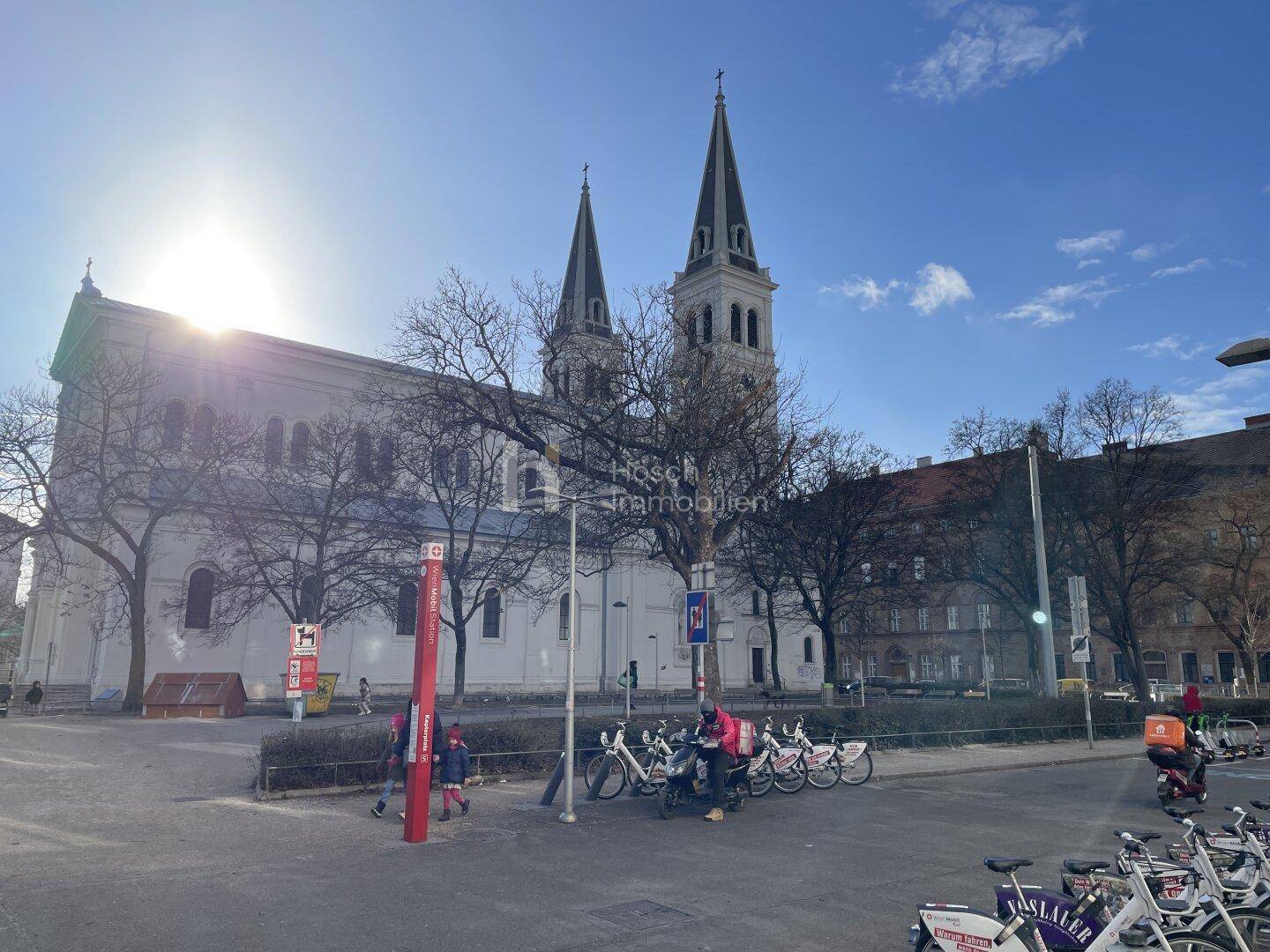 Historische Kirche mit zwei Türmen auf einem sonnigen Platz in der Stadt.