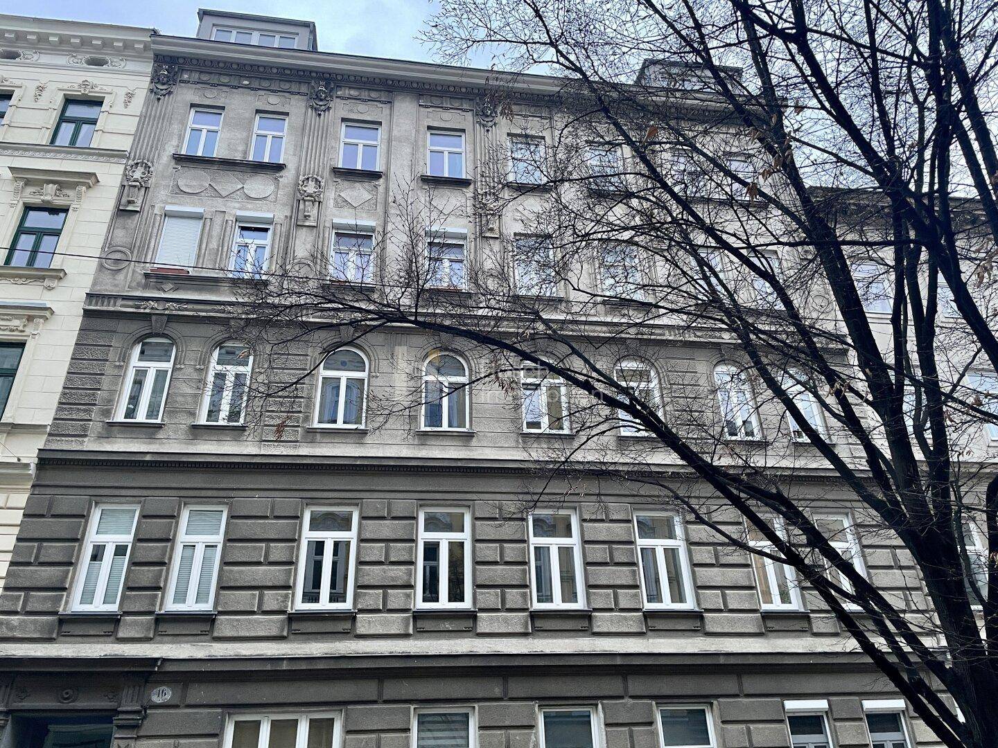 Ansicht eines klassischen Wiener Altbaus mit charakteristischer Fassadengestaltung und Bäumen.