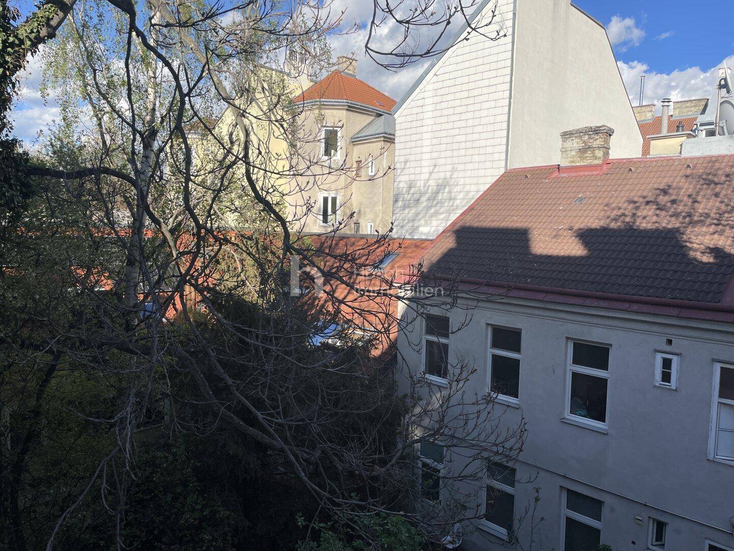 Blick über Dächer und Bäume auf die umliegende Stadtlandschaft an einem sonnigen Tag.