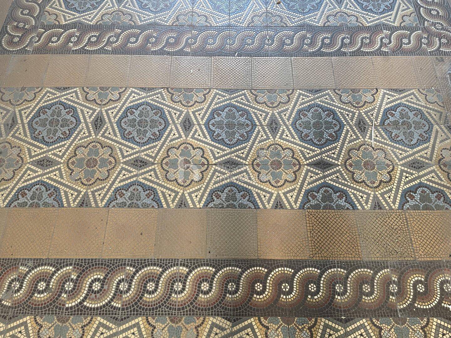Detailaufnahme eines historischen Mosaikbodens mit komplexen Mustern und Bordüren.