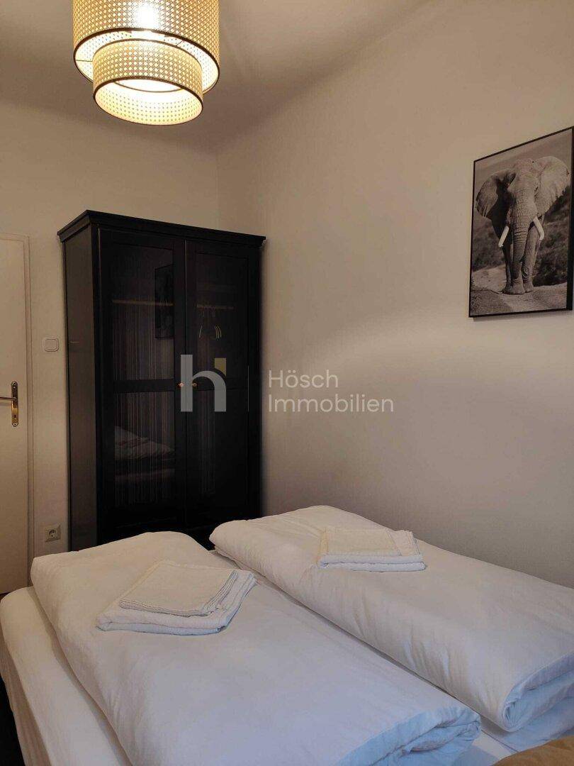 Schlafzimmer mit dunklem Kleiderschrank und einem Teil des Bettes, das zum Entspannen einlädt.