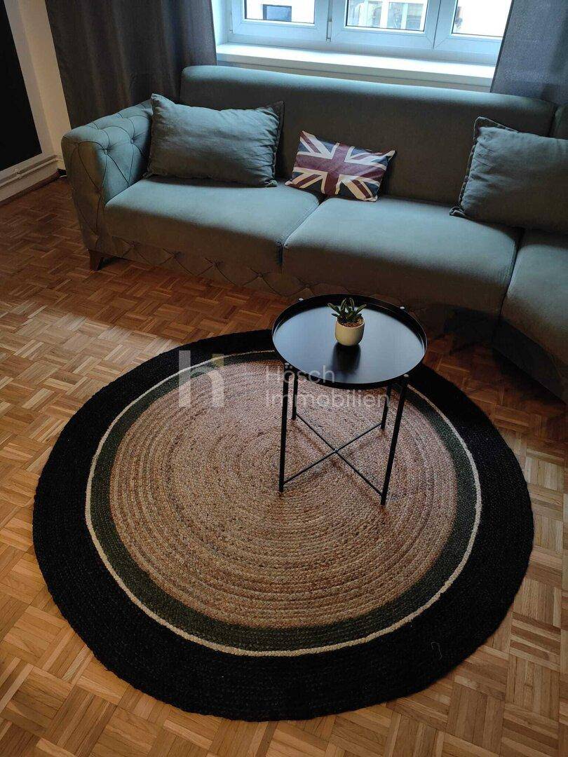 Wohnzimmer mit bequemer Couch, rundem Teppich und kleinem Beistelltisch.