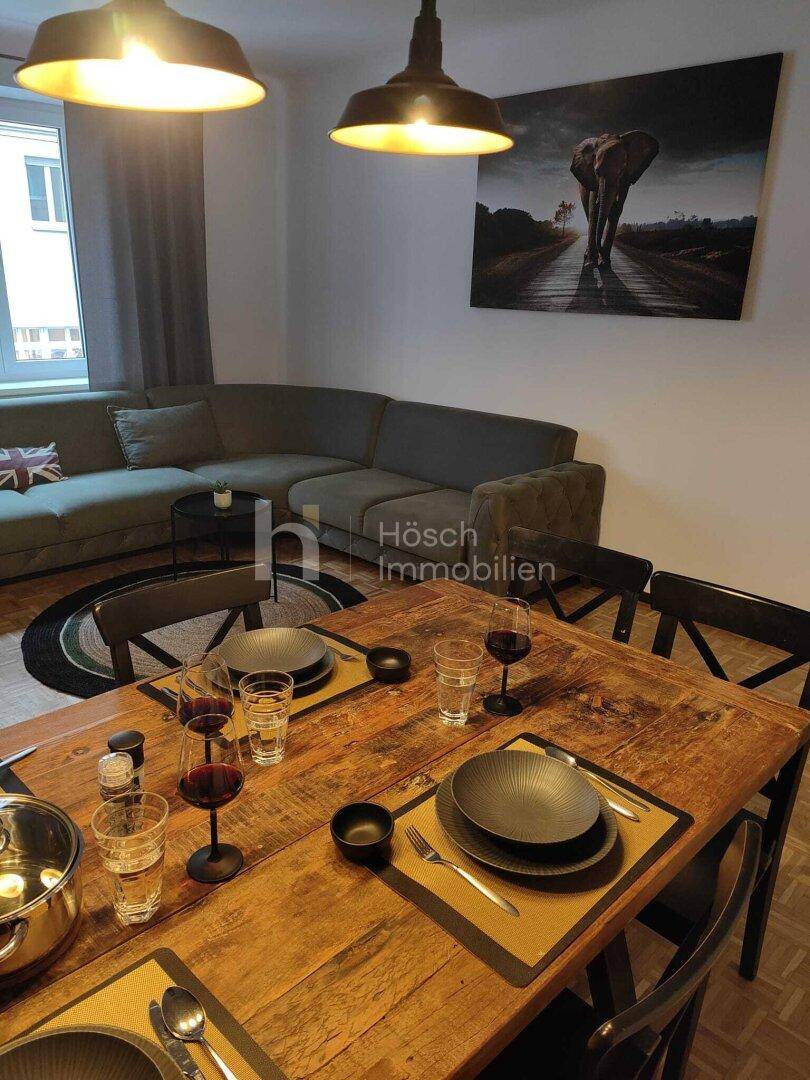 Offener Wohn-Essbereich mit Esstisch, Sofa und Elefantenbild an der Wand.