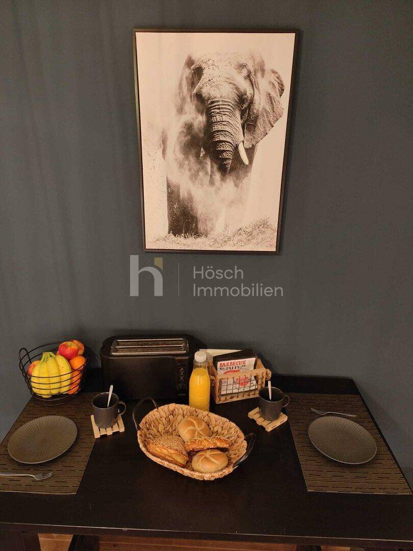 Stehtisch mit Frühstücksutensilien, Toaster und einem Elefantenbild an der Wand.