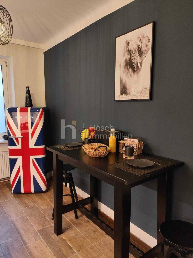 Kleine Küche mit Stehtisch, Hockern und einem auffälligen Kühlschrank im Union Jack Design.