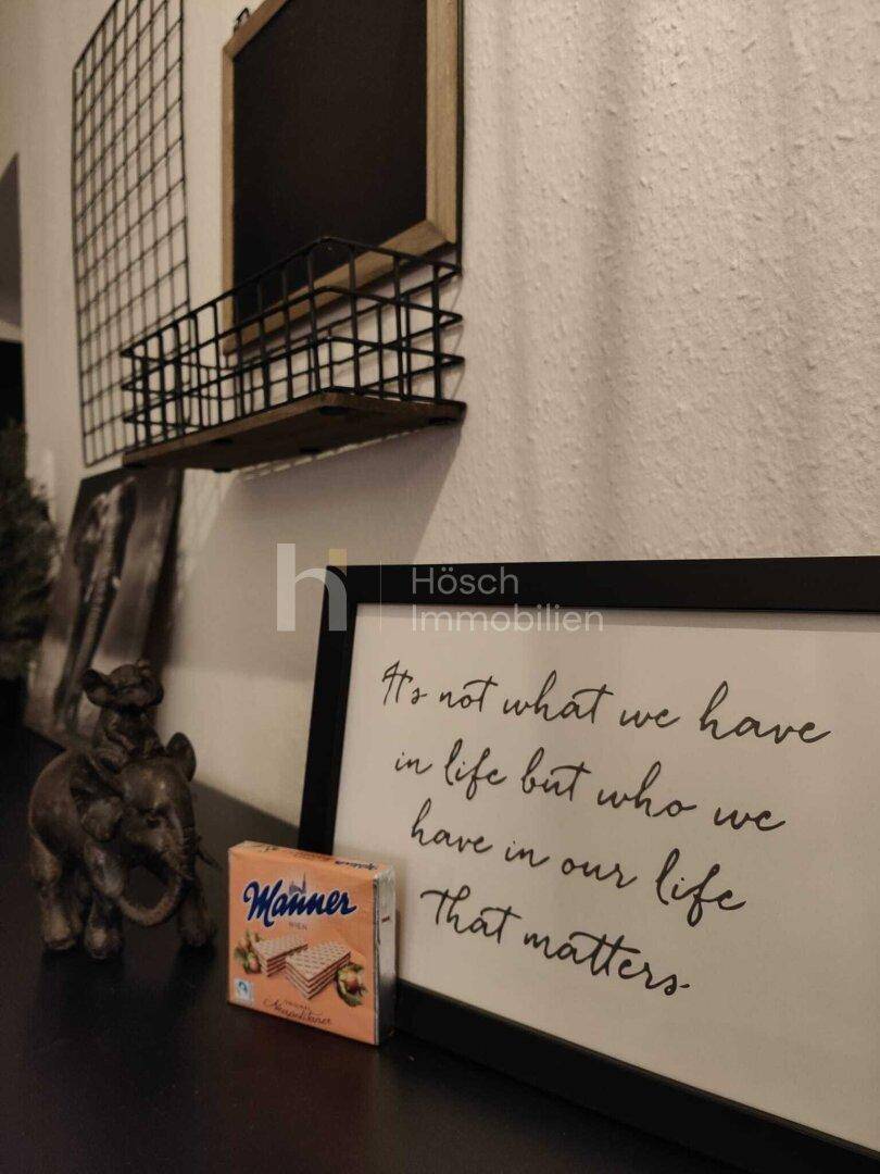 Detailansicht der Dekoration auf der Kommode im Flur mit gerahmtem Spruch.