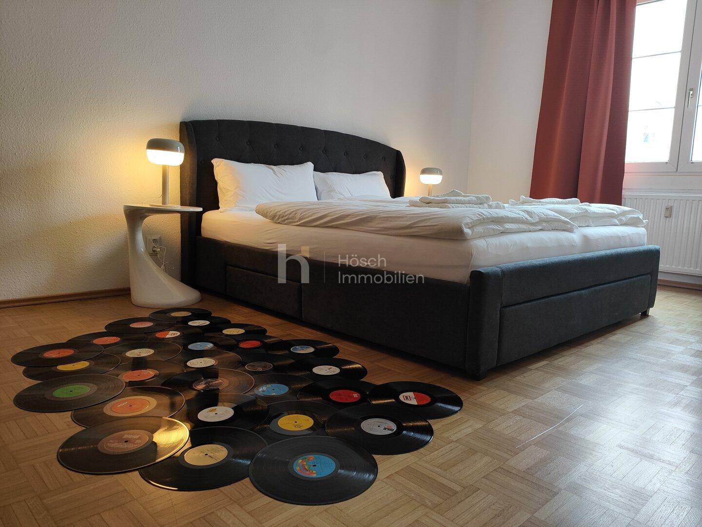 Gemütliches Schlafzimmer mit Doppelbett, Nachttischen und einer einzigartigen Dekoration aus Schallplatten auf dem Boden.