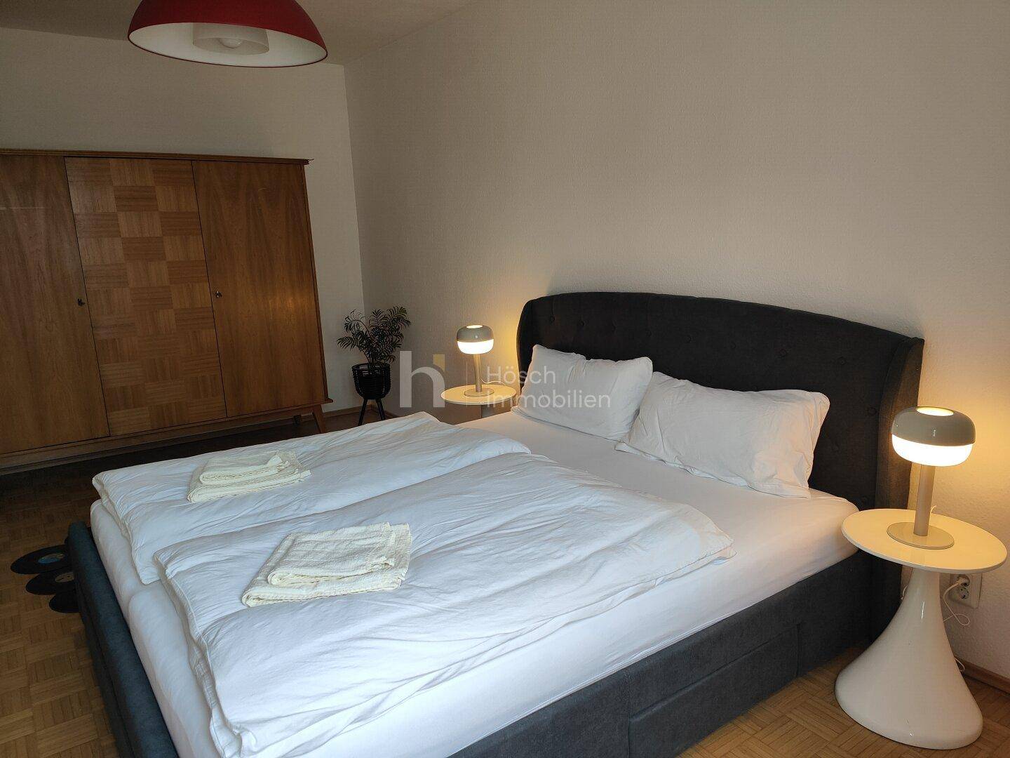 Schlafzimmer mit Doppelbett, Nachttischen und einem klassischen Holzschrank, der Stauraum bietet.