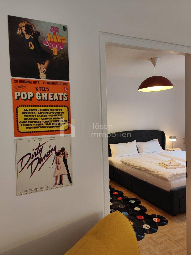 Blick in ein Schlafzimmer mit Doppelbett und kreativer Bodendekoration aus Schallplatten.