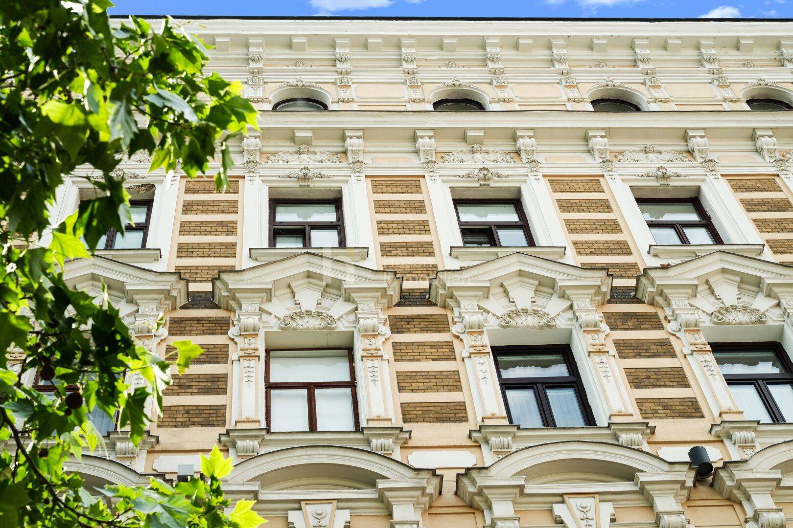 Detailansicht der kunstvollen Fassadenornamente und Fenster eines historischen Gebäudes.
