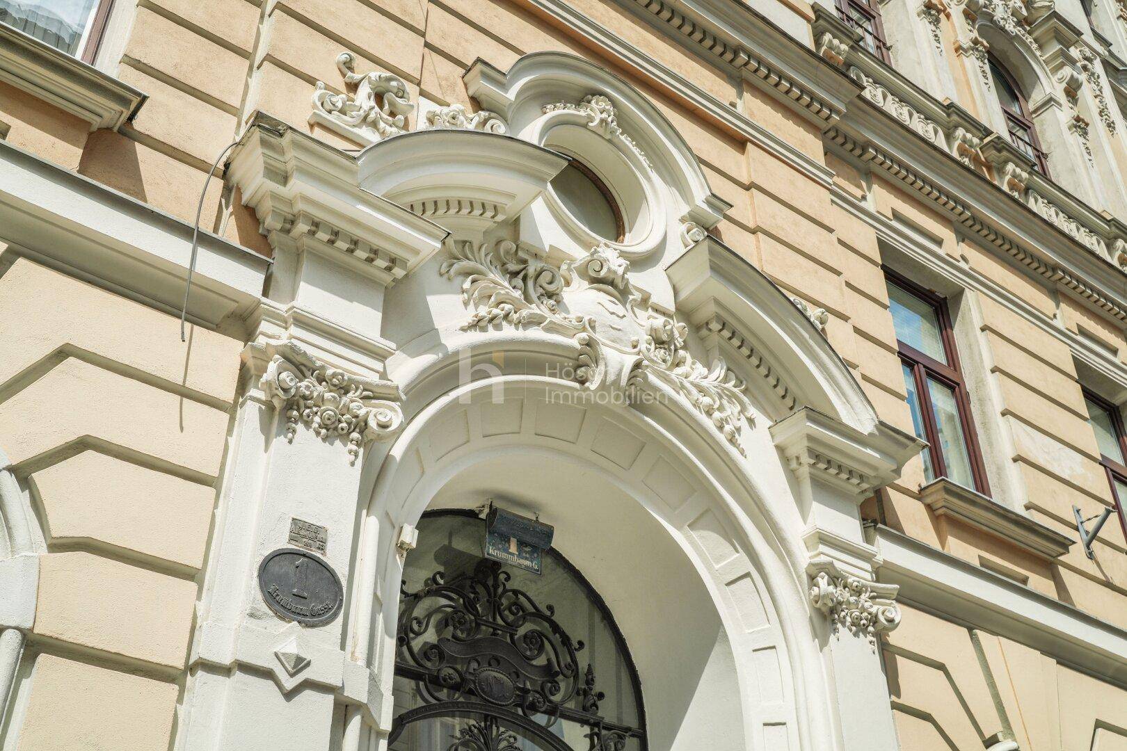 Prunkvoller Eingangsbereich mit reich verzierten Stuckelementen und schmiedeeisernem Tor.