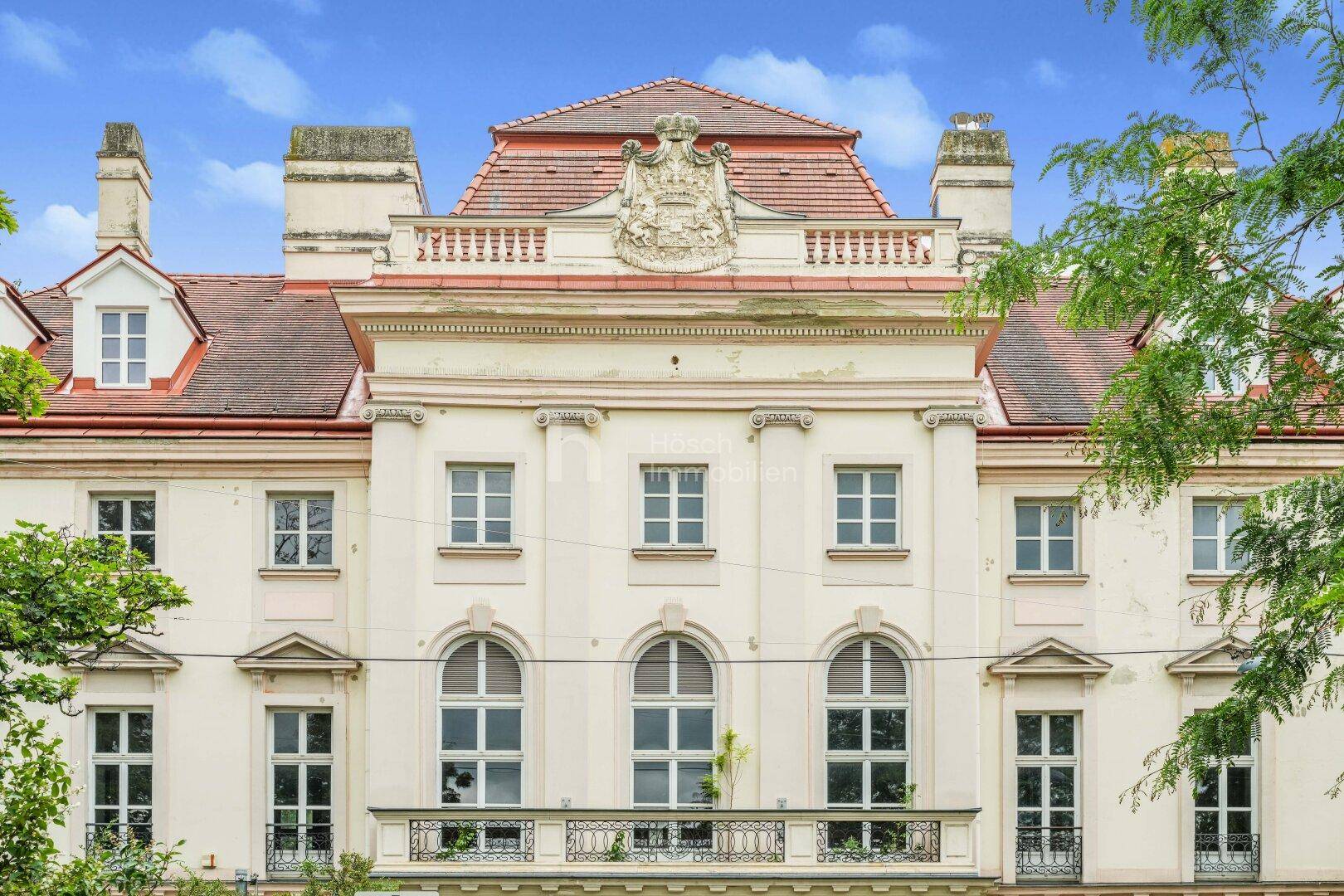 Detailansicht der historischen Fassade mit eleganten Fenstern, Balkon und dekorativen Elementen.