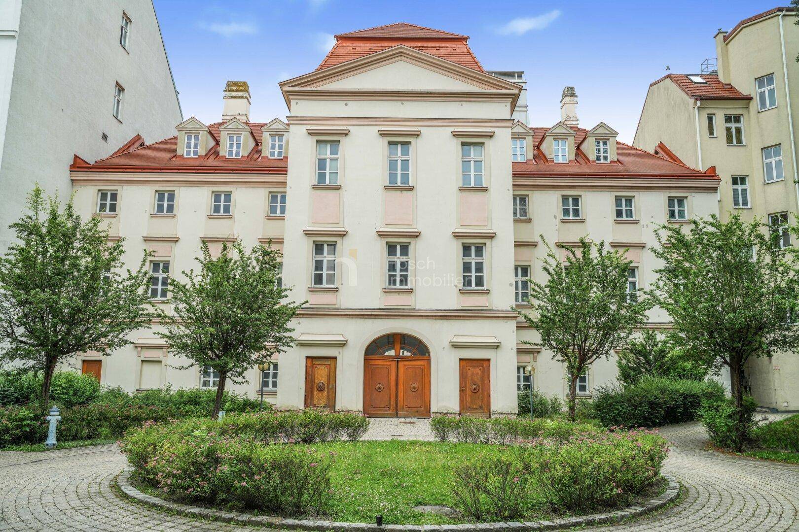 Historisches Gebäude mit gepflegtem Innenhof und kreisförmiger Grünfläche.