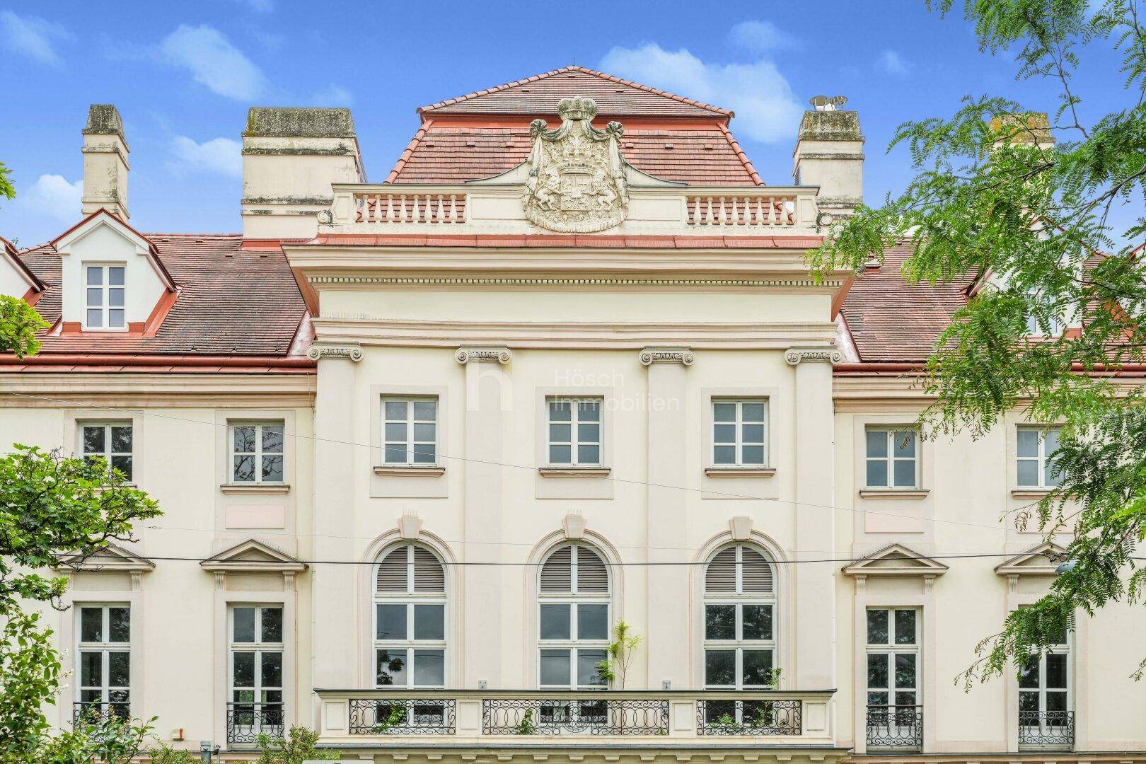 Detailansicht der historischen Fassade mit eleganten Fenstern, Balkon und dekorativen Elementen.