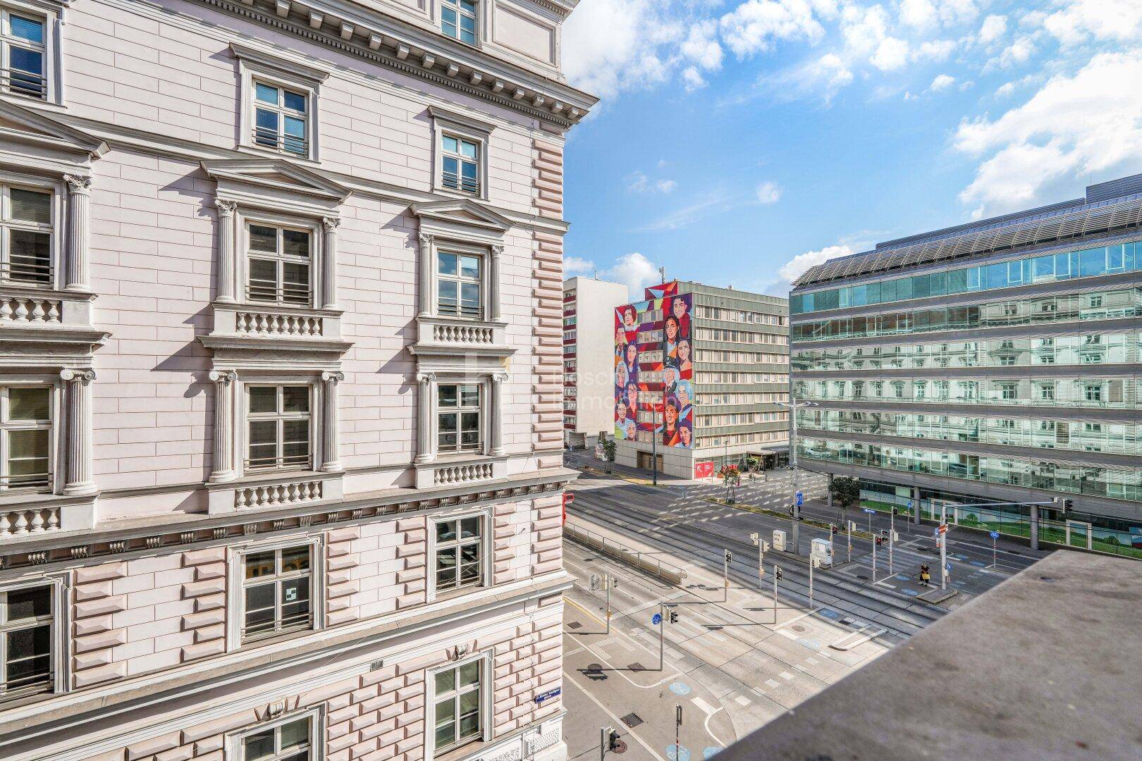 Blick von einem Balkon auf die belebte Stadtstraße und umliegende Gebäude.