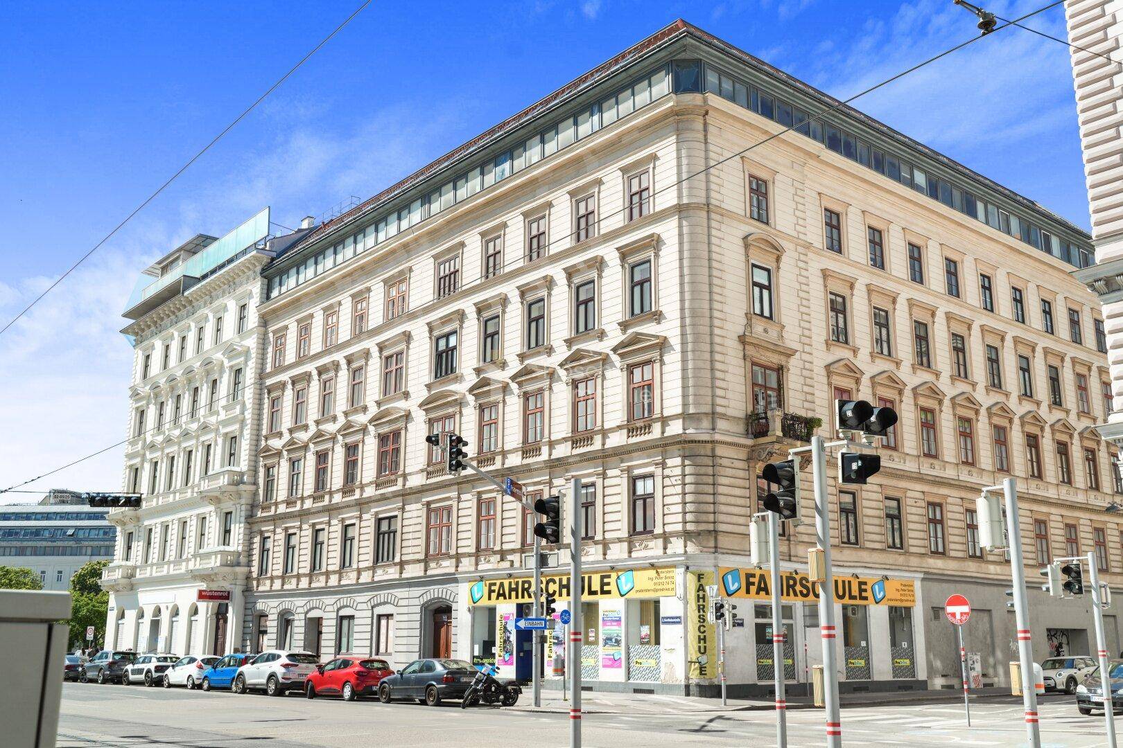Historisches Eckgebäude mit Geschäften im Erdgeschoss und belebter Stadtstraße.