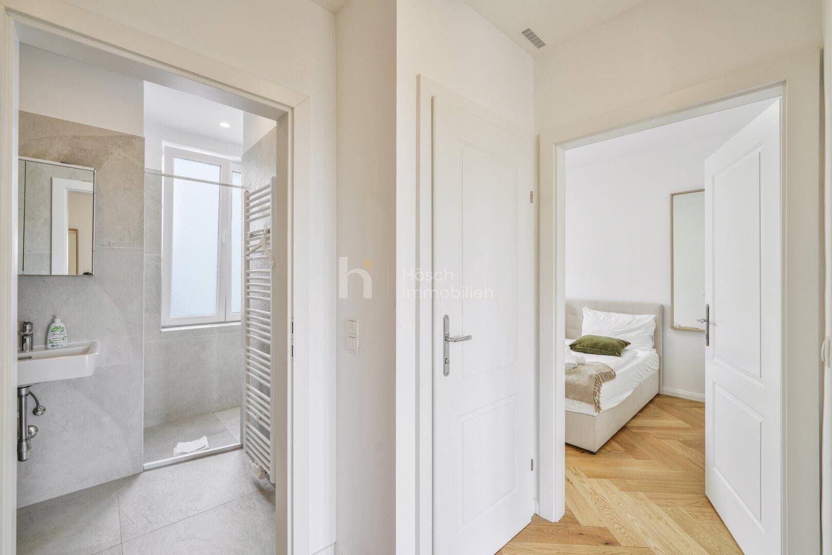 Heller Flur mit Zugang zu einem modernen Badezimmer und einem Schlafzimmer.