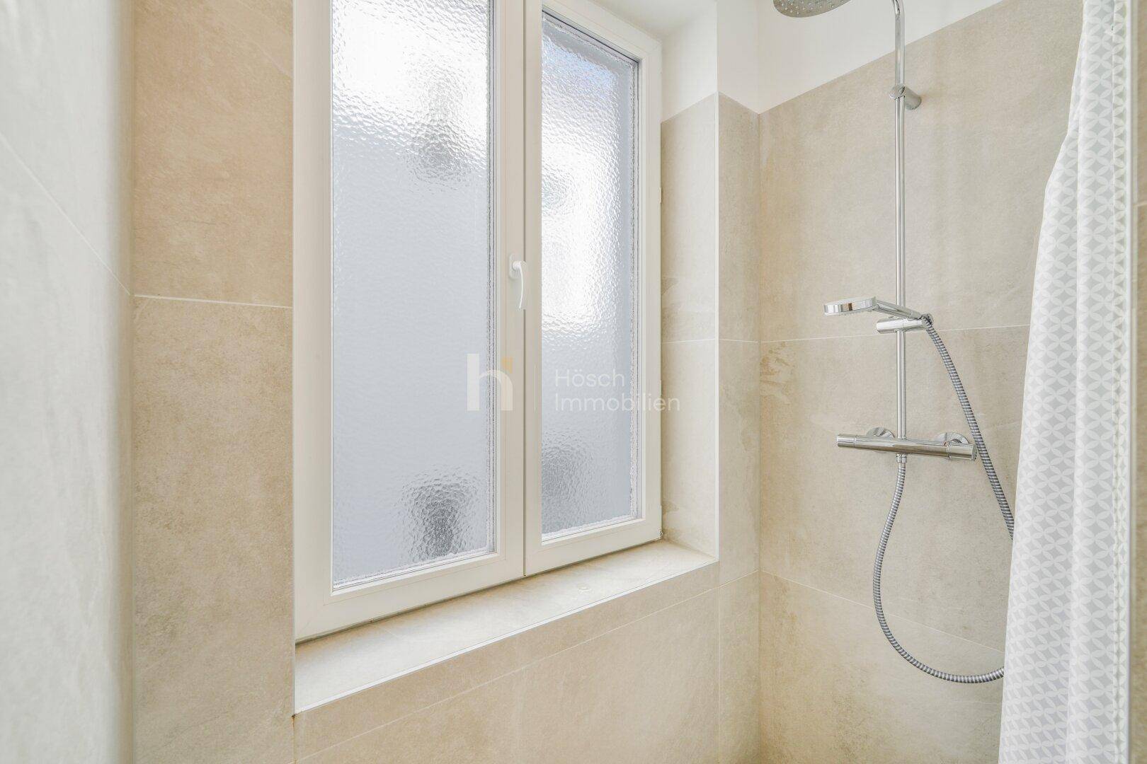 Duschbereich im Badezimmer mit modernen Fliesen und einem Fenster.