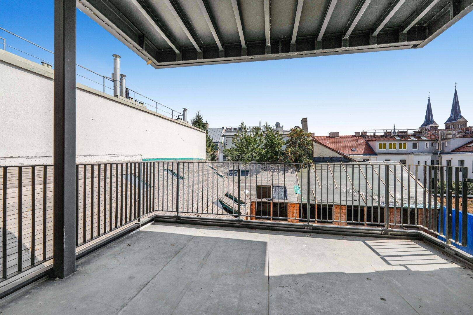 Leere Dachterrasse mit Blick auf die umliegenden Gebäude und den blauen Himmel.