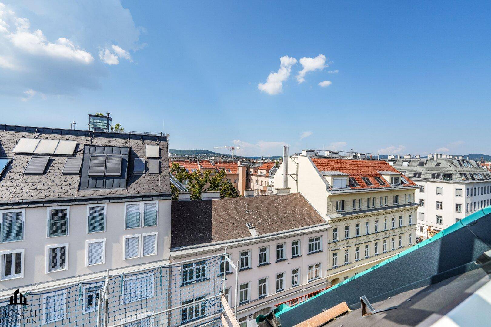 Weitblick über die Dächer der Stadt mit vielen Gebäuden und blauem Himmel.