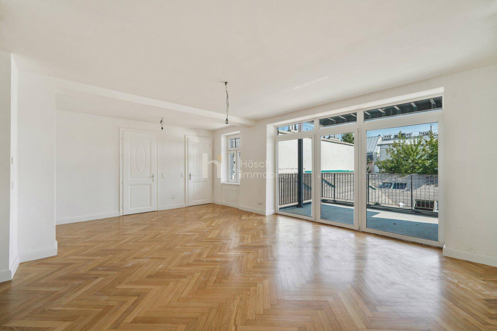 Helles, unmöbliertes Zimmer mit Parkettboden und großem Terrassenzugang.