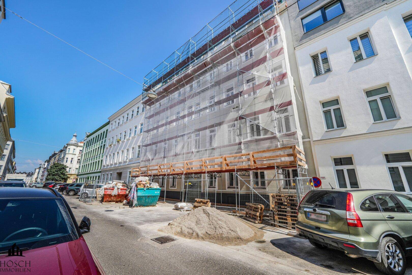Gebäudefassade unter Gerüst, deutet auf Renovierungsarbeiten oder Neubau hin.