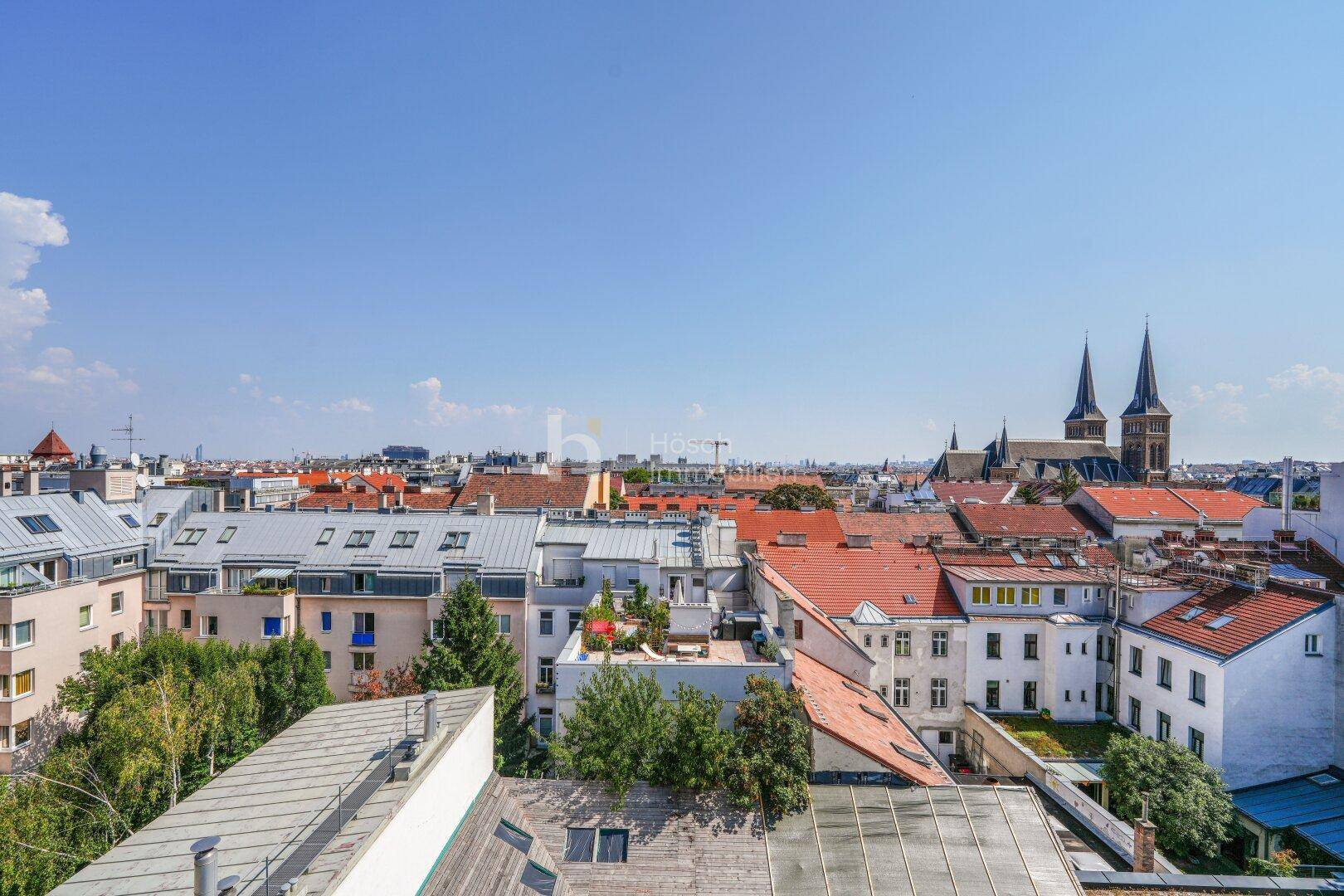 Panoramablick über die Dächer der Stadt mit historischen Kirchtürmen im Hintergrund.