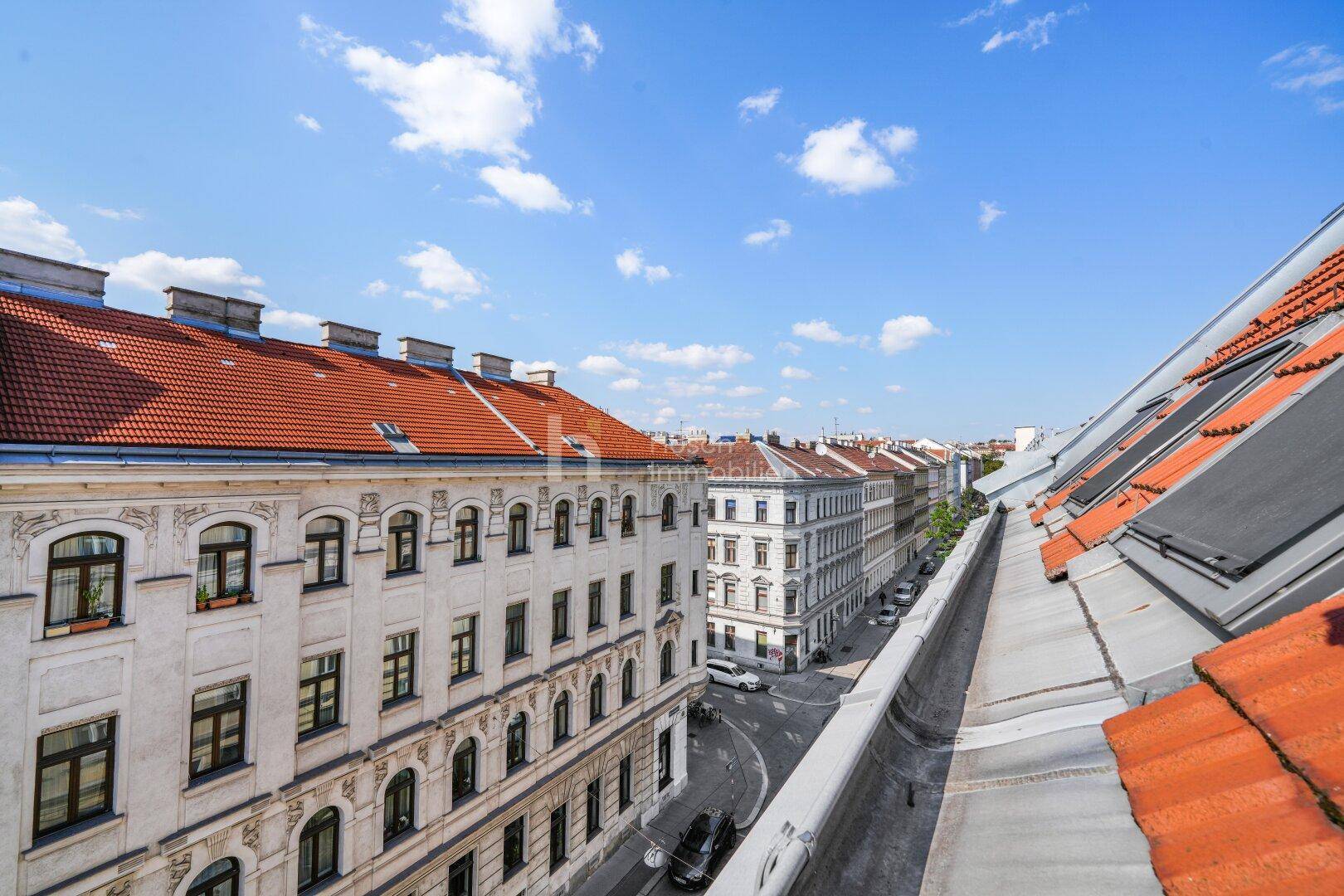 Weitläufiger Blick über die Dächer der Stadt und die umliegenden Gebäude unter blauem Himmel.