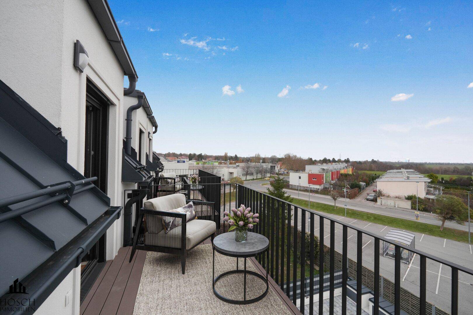 Balkon mit Sitzgelegenheiten und weitem Blick über die städtische Umgebung und Landschaft.