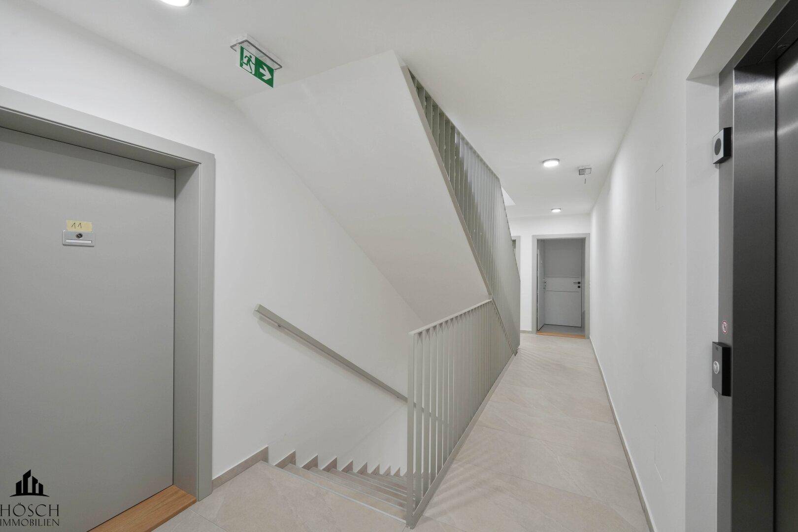 Heller Flur mit Treppenhaus und modernem Aufzug im Gebäude.