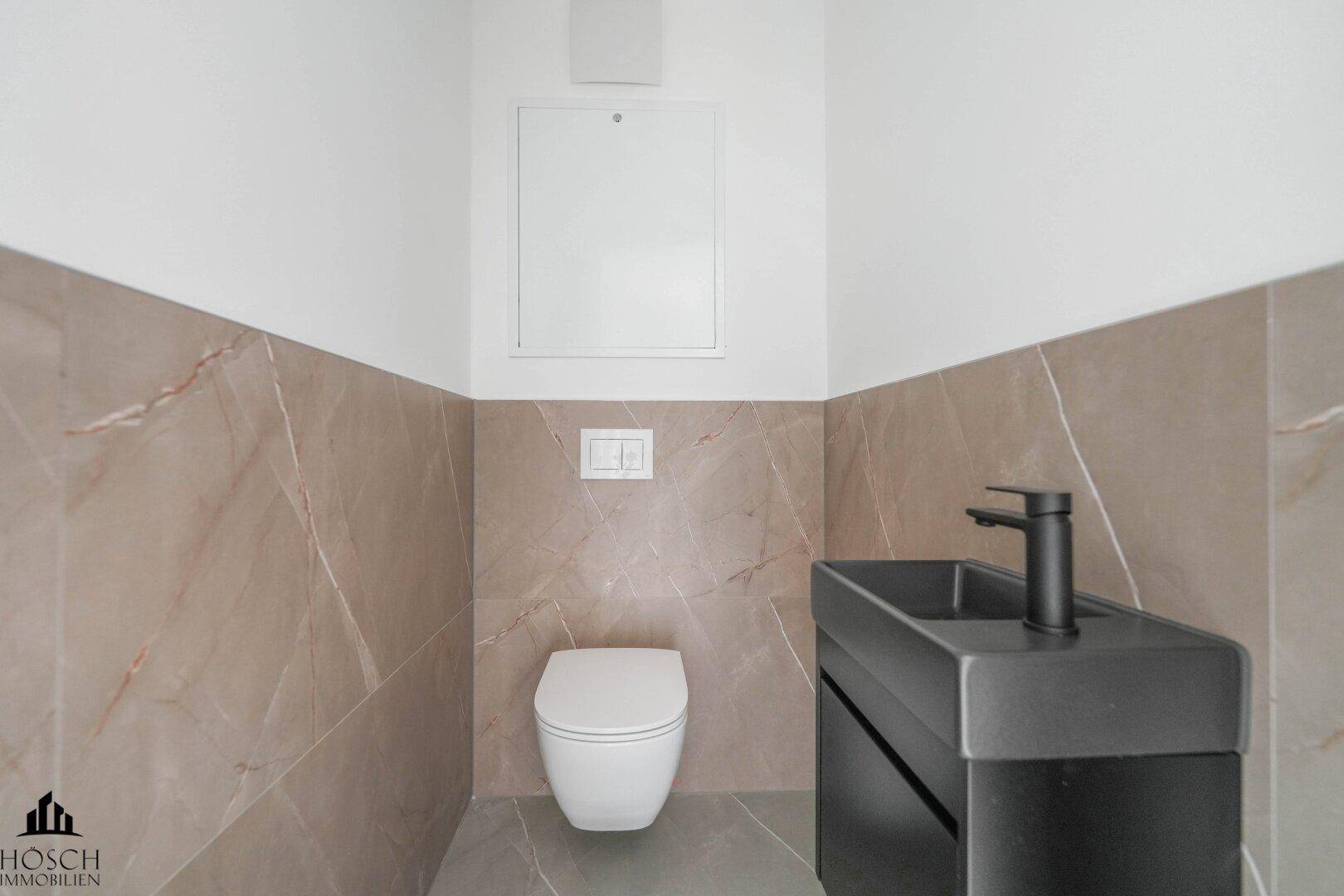 Modernes Gäste-WC mit Wand-WC, kleinem Waschbecken und Fliesenboden.