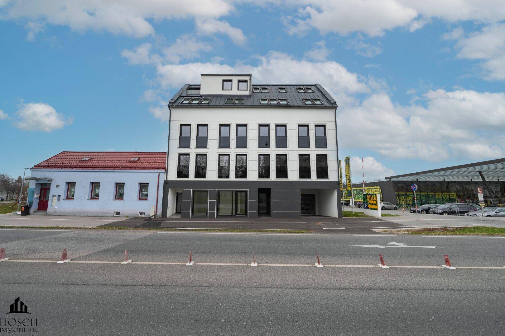 Modernes Gebäude mit weißer und grauer Fassade an einer Straße gelegen.