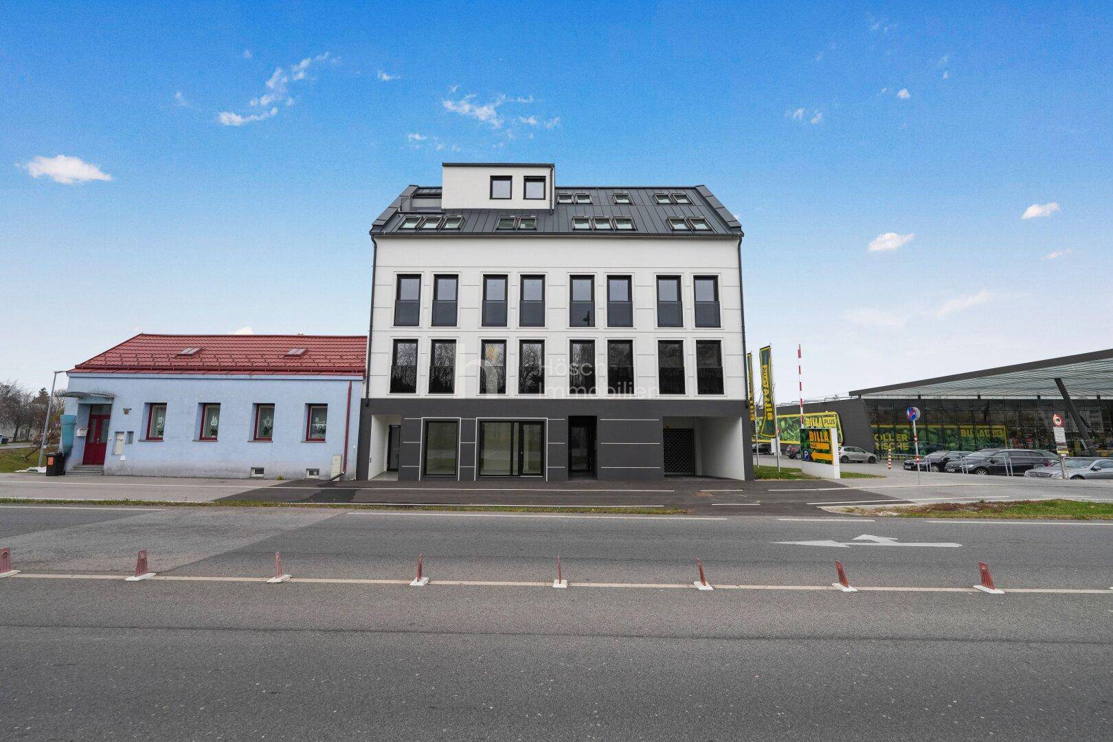 Moderne Wohnanlage mit Geschäften im Erdgeschoss und einer klaren, zeitgenössischen Architektur.