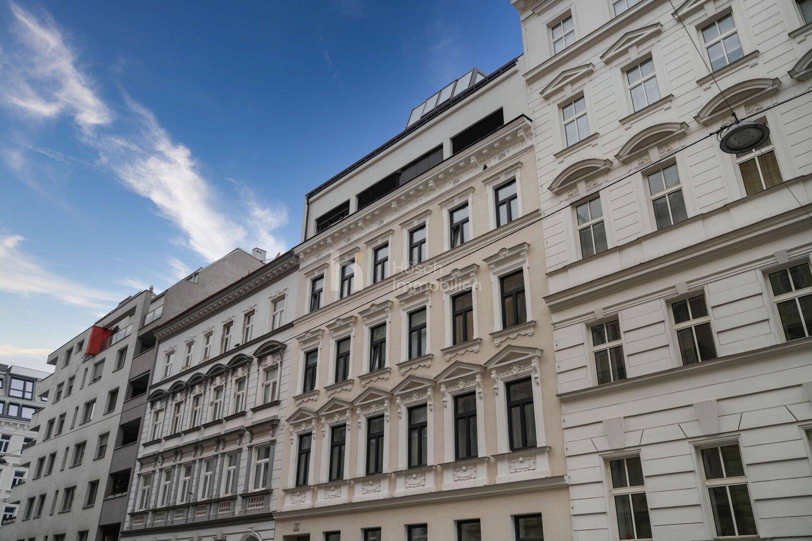 Historische Gebäudefassade mit modernen Elementen und klarem Himmel.