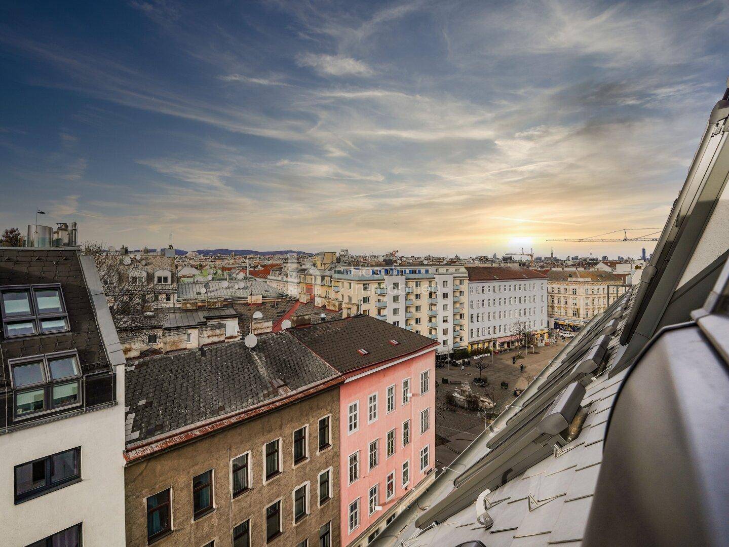 Weitläufiger Blick über die Dächer der Stadt bei Sonnenuntergang.