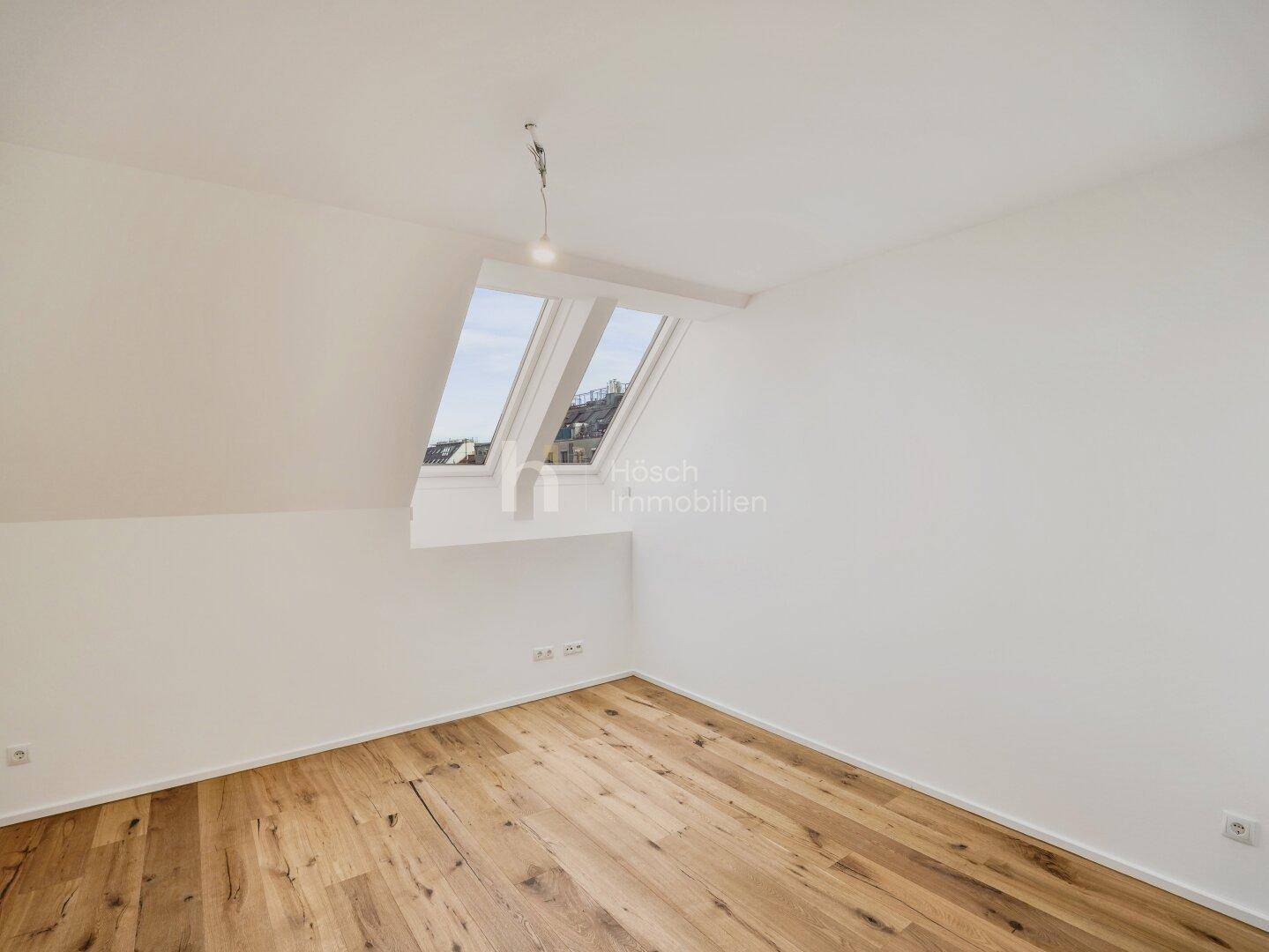 Ruhiges Zimmer im Dachgeschoss mit Holzboden und Dachfenstern, ideal als Schlaf- oder Arbeitszimmer.