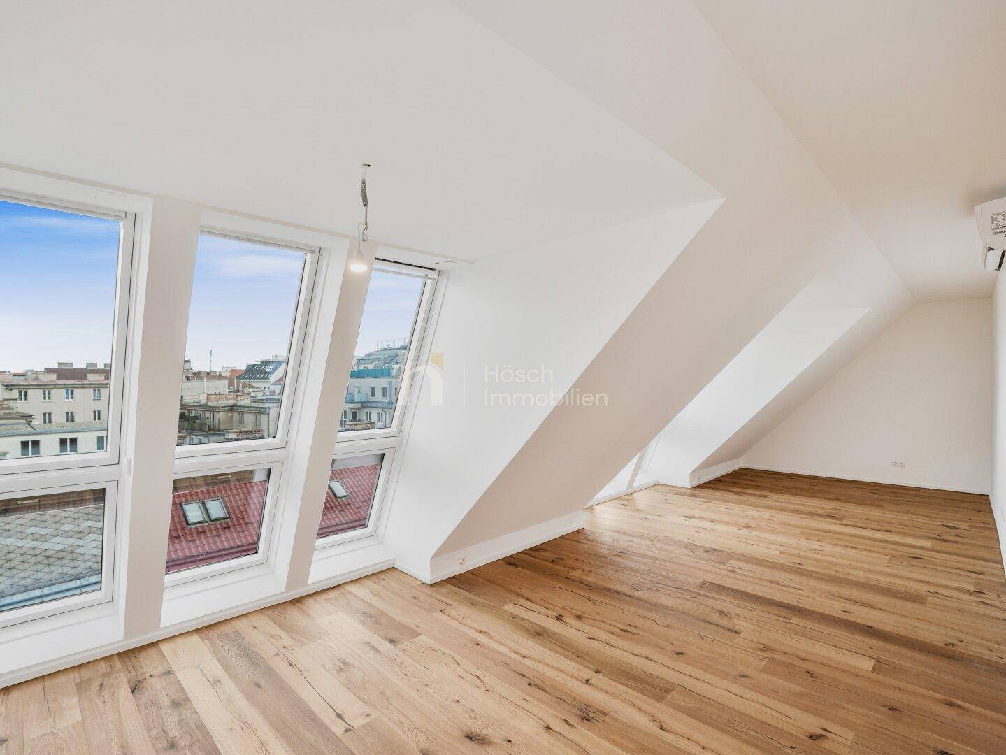 Geräumiger, heller Raum im Dachgeschoss mit großen Fenstern und Holzboden, ideal als Wohnbereich.