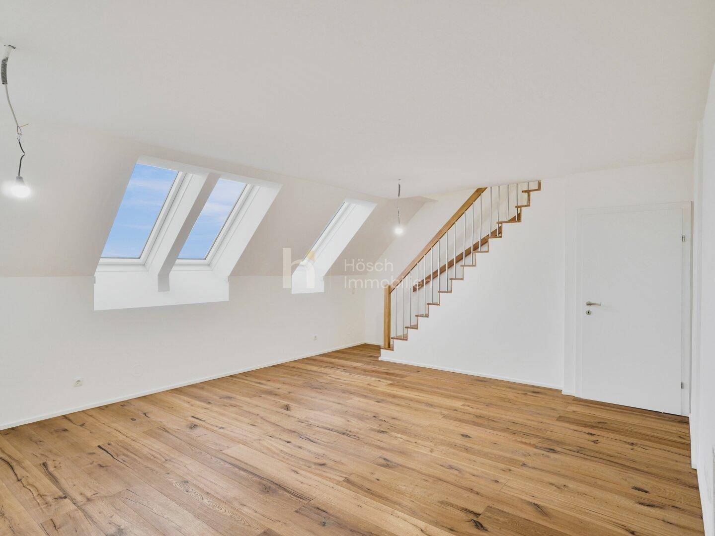 Geräumiger Dachgeschossraum mit Holzboden, Dachfenstern und einer Holztreppe, bietet viel Potenzial.