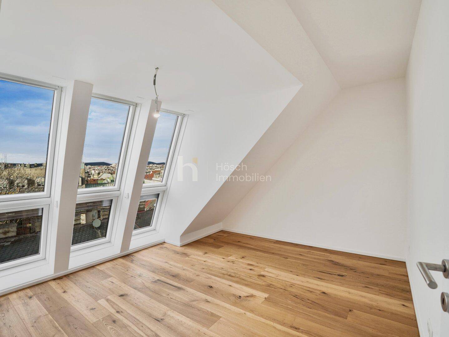 Großer, heller Raum im Dachgeschoss mit Holzboden und breiten Fenstern, ideal für individuelle Gestaltung.