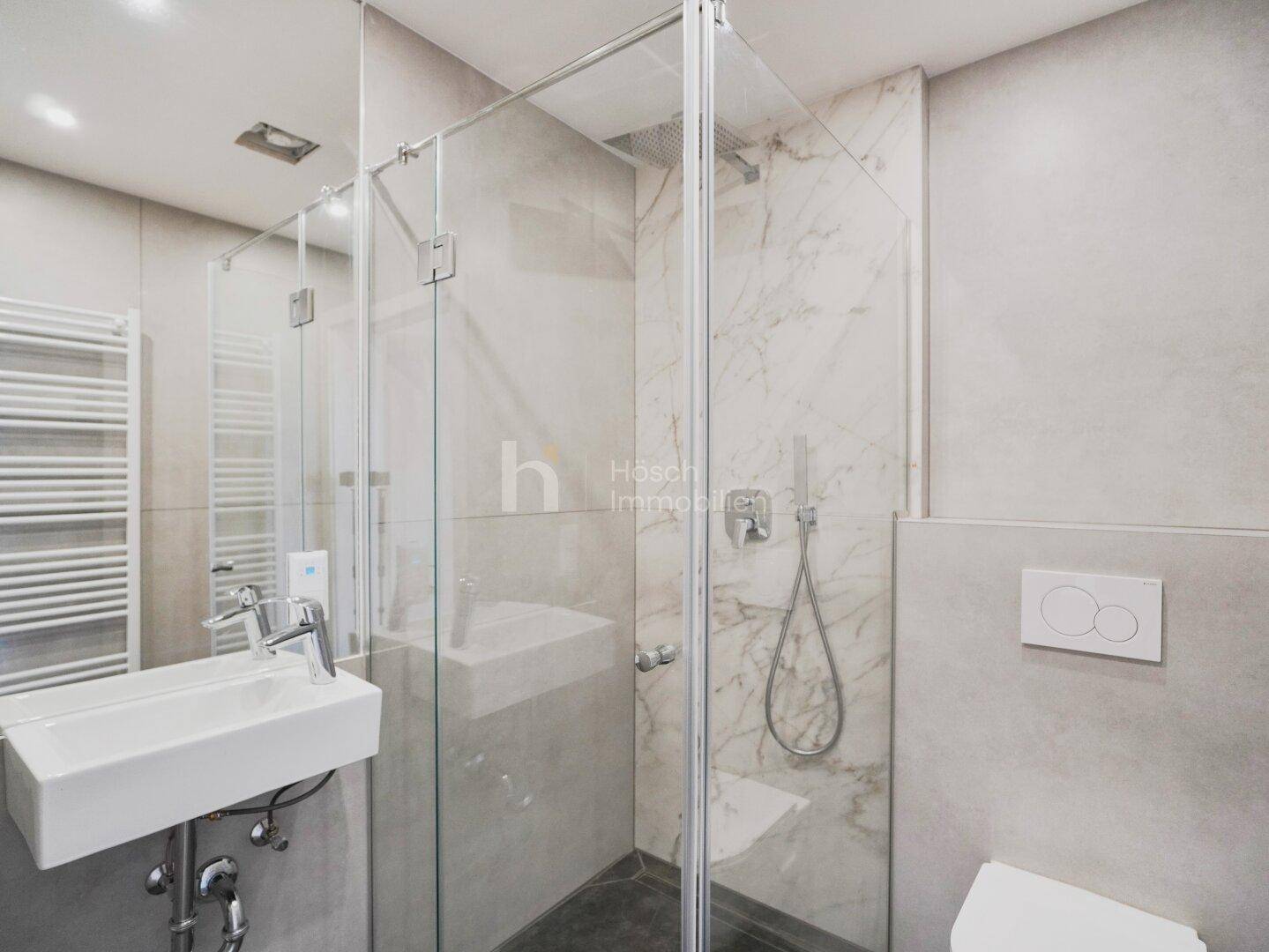 Modernes Badezimmer mit Duschkabine, Einzelwaschbecken, Wand-WC und hellen, zeitgemäßen Fliesen.