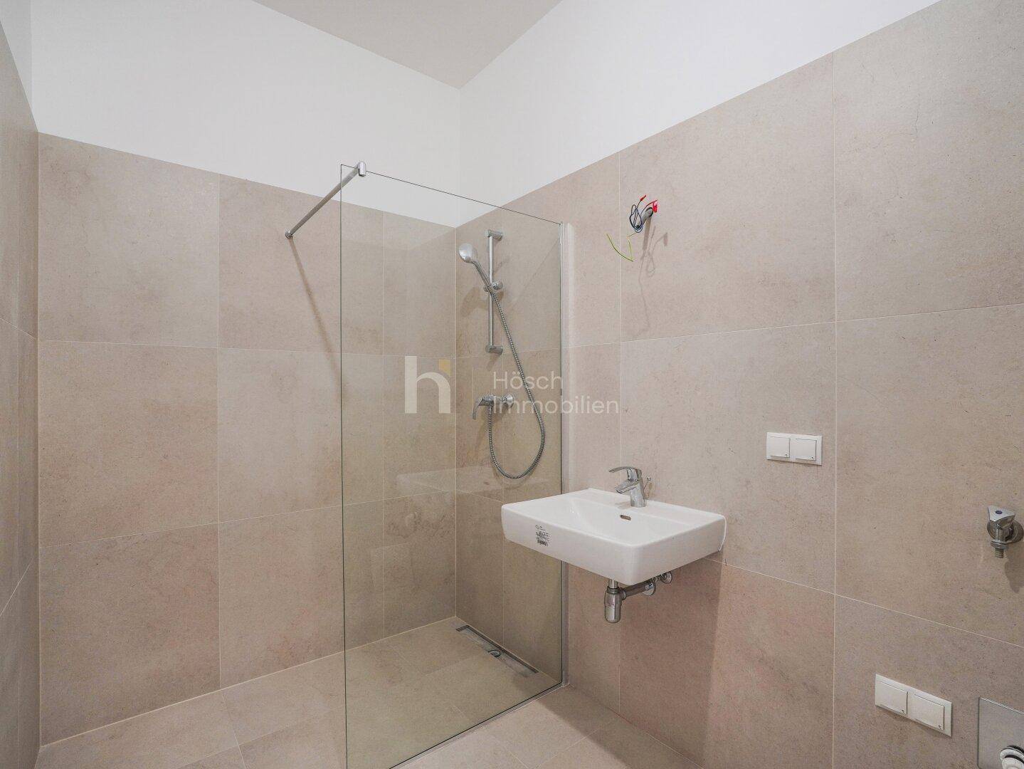 Modernes Badezimmer mit begehbarer Dusche, Einzelwaschbecken und hellen Fliesen.